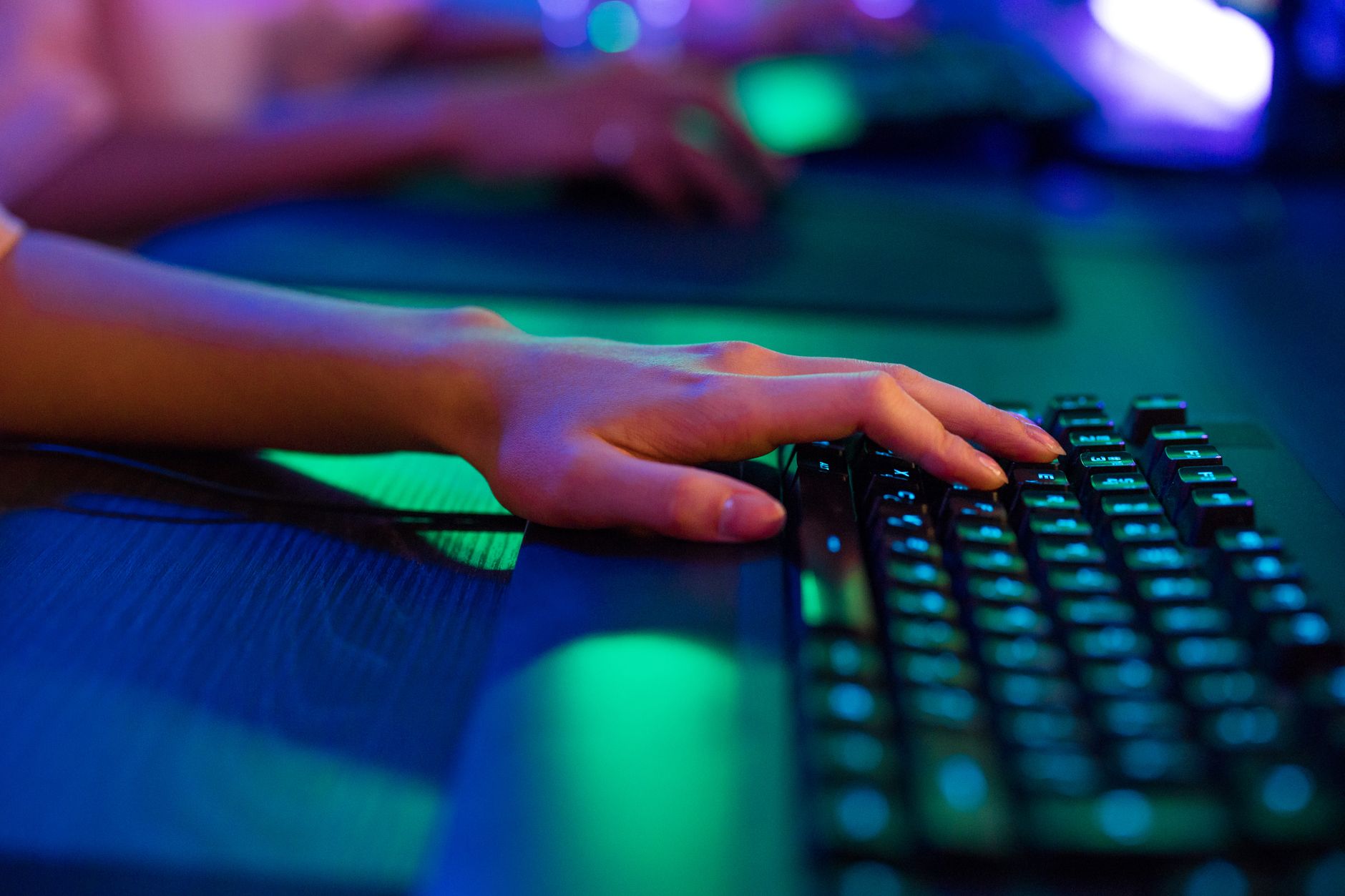 asus rog keyboard not working - A close-up image of a person's hand typing on a keyboard, illuminated by neon lights, creating a vibrant tech atmosphere.
