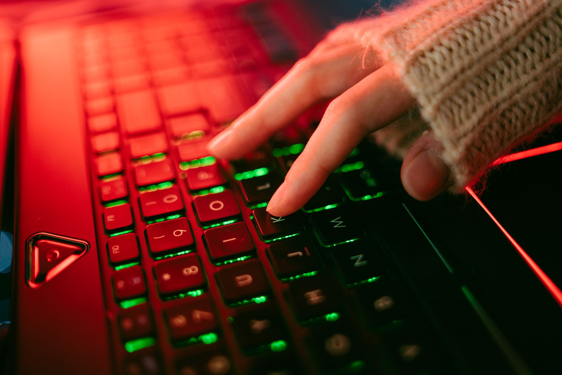 asus rog keyboard not working - A hand typing on a backlit keyboard in a dark ambiance, highlighting vibrant key illumination.