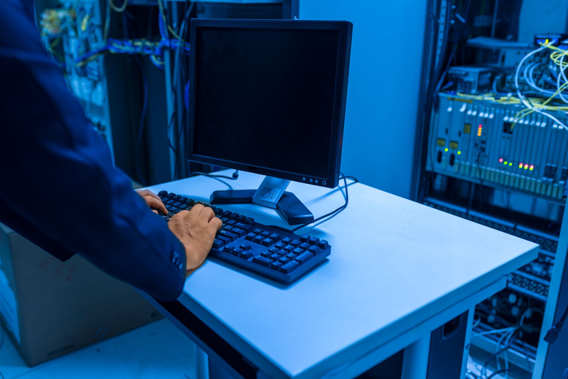 computer says no internet - An IT professional operates a computer in a server room, managing network systems and connected devices.