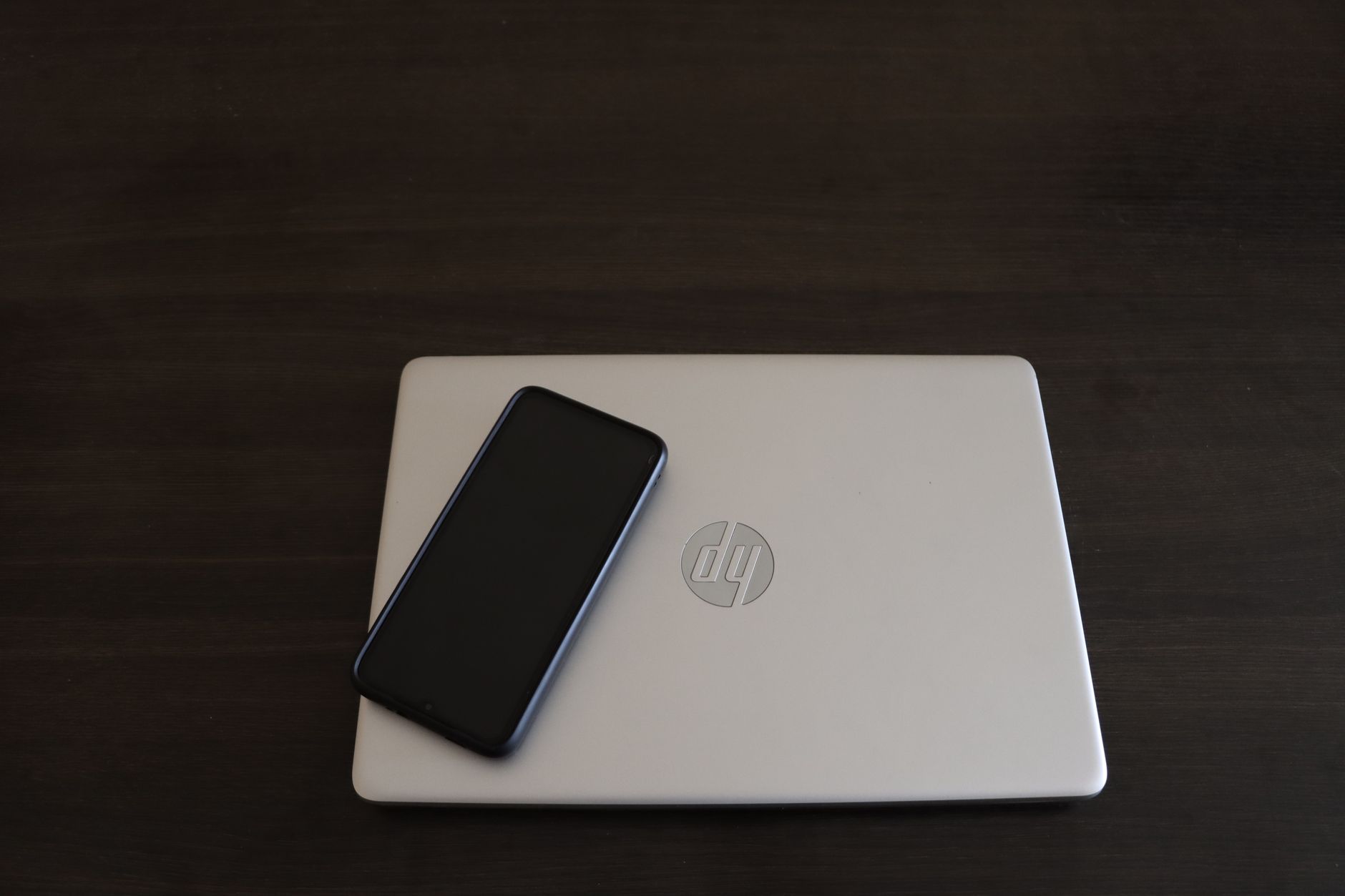 computer says no internet connection but there is - Close-up of a smartphone resting on an HP laptop, symbolizing modern technology integration.