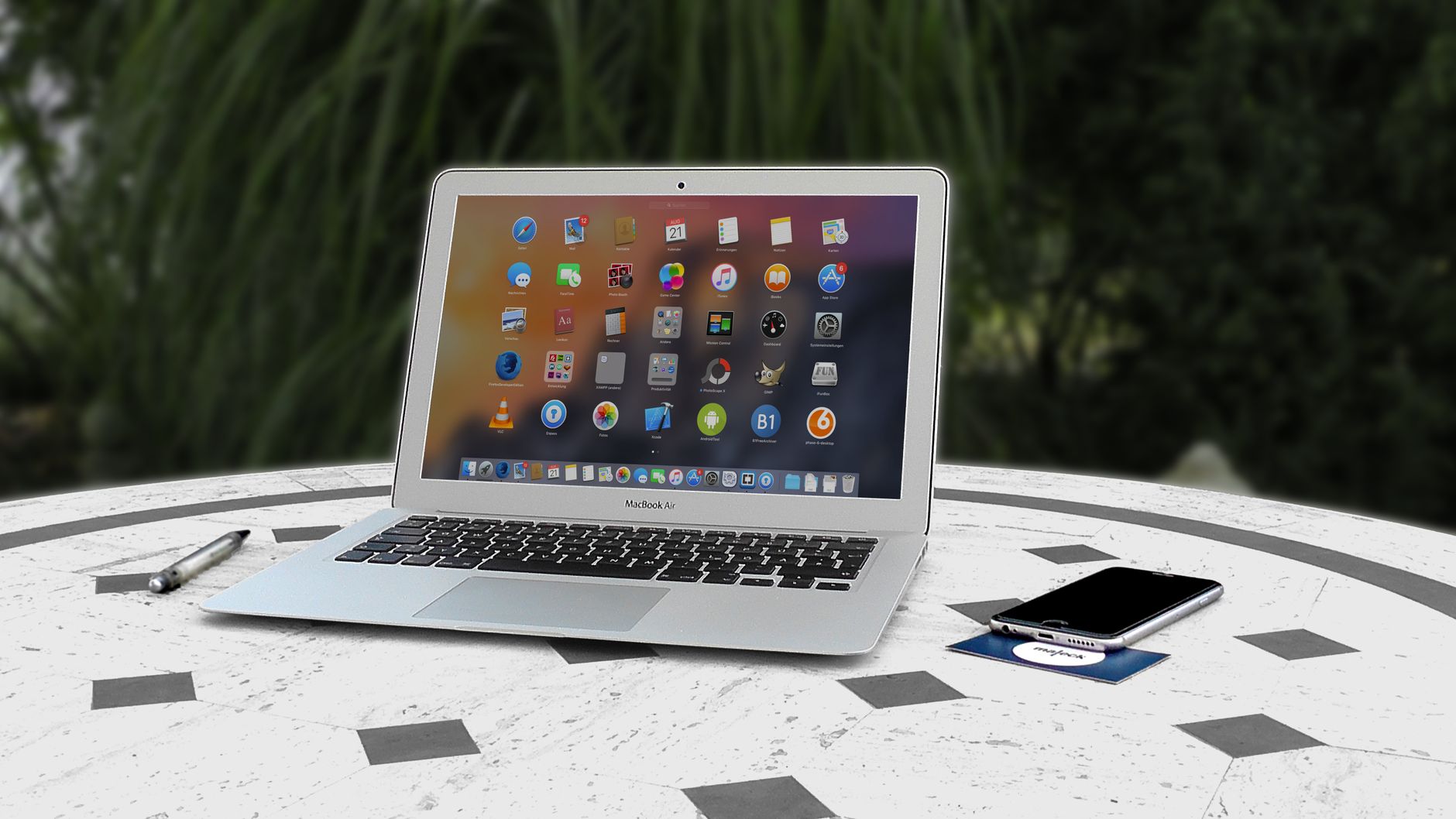 computer says no internet connection but there is - Open laptop with app icons displayed, smartphone and pen on white table outdoors.