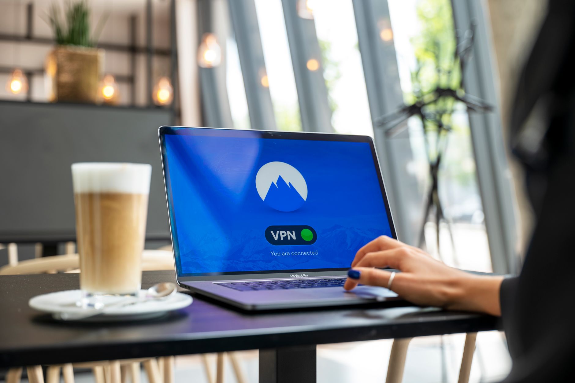 connected to internet but no wifi - A person using a laptop with a VPN connection in a modern cafe setting, showcasing remote work and internet security.