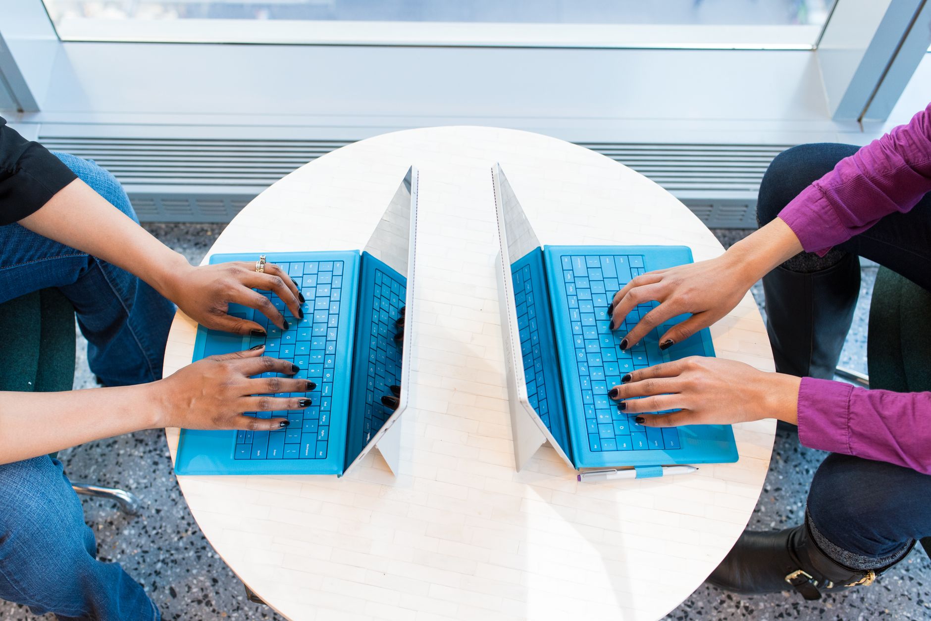 hotspot not working on laptop - Two people working on blue laptops at a round table, focusing on teamwork and technology.