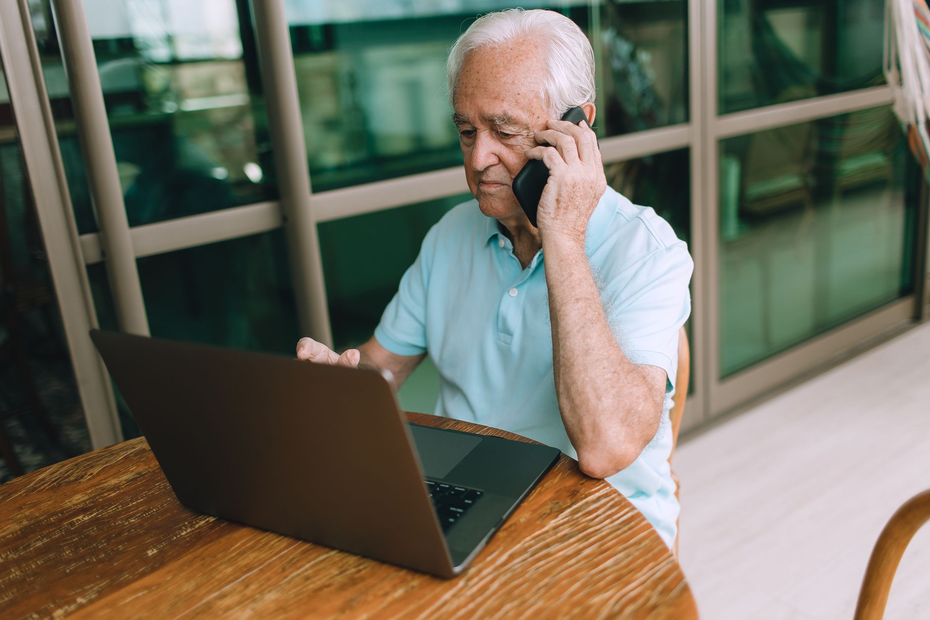 hotspot not working on laptop - Elderly man multitasking, using laptop and phone at home. Lifestyle image.
