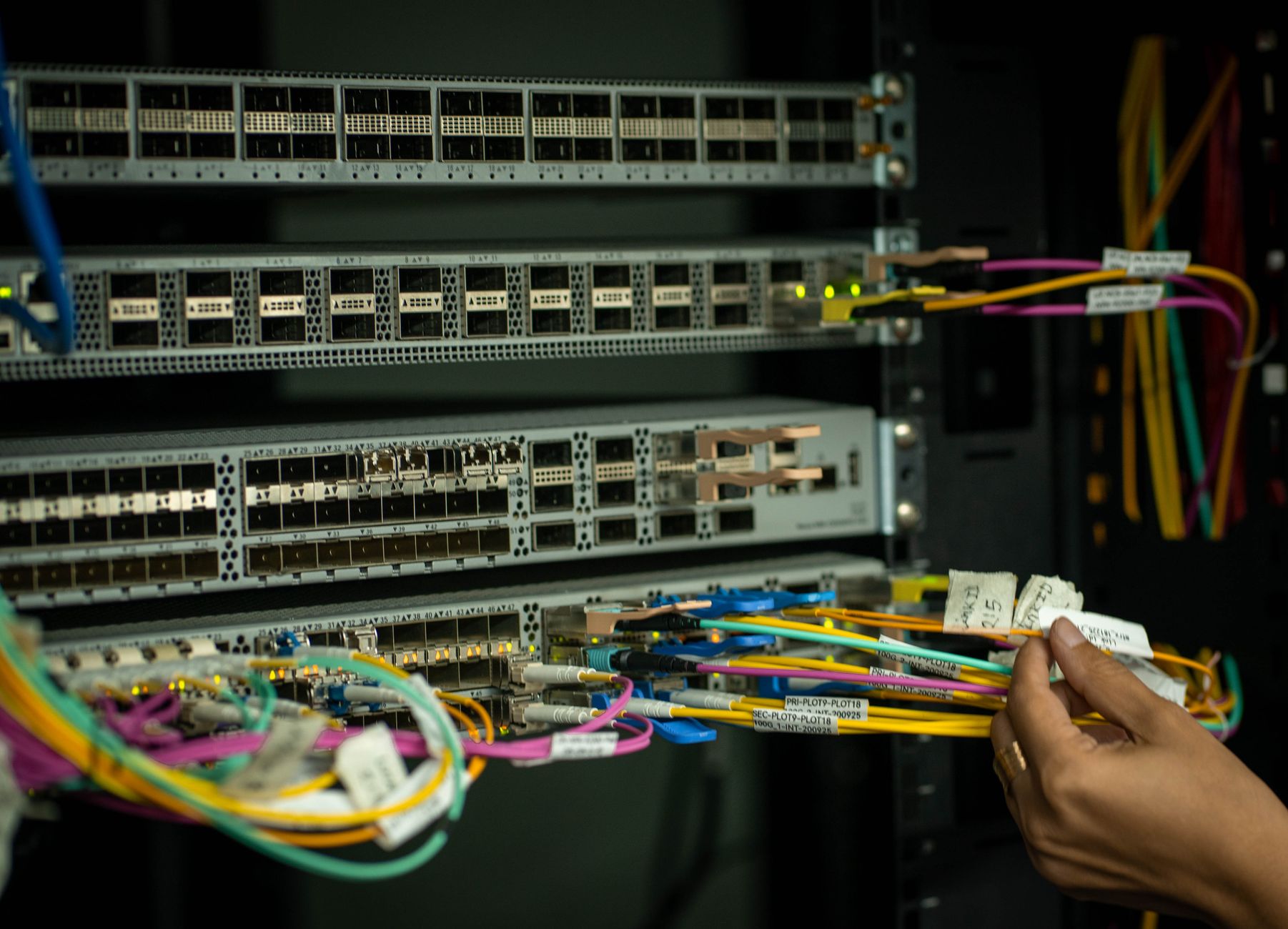 how to fix limited connection in wifi - A hand managing fiber optic cables in a server room, showcasing modern connectivity.