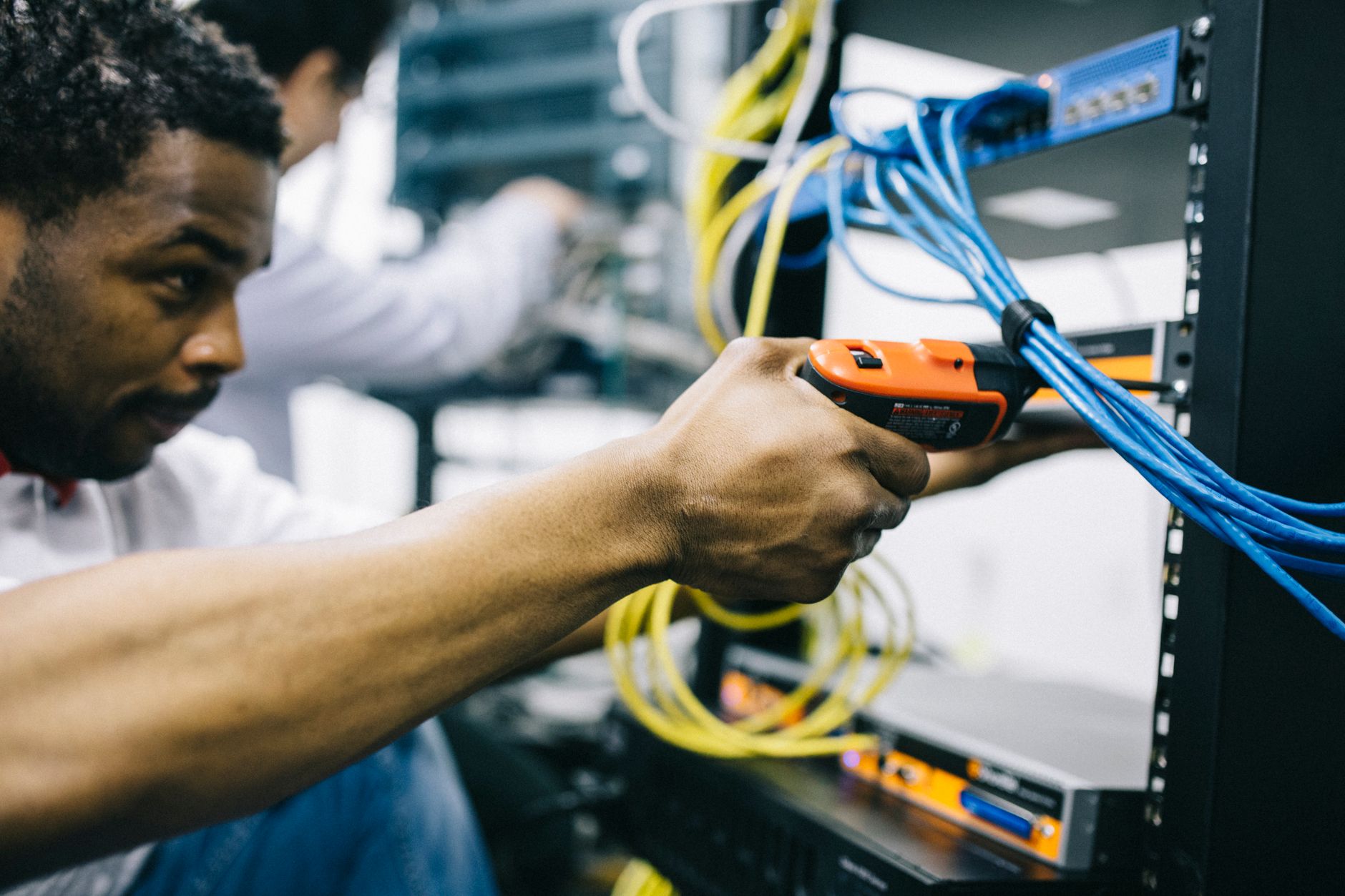 how to troubleshoot a router - Side view crop concentrated African American engineer repairing equipment by using electric screwdriver