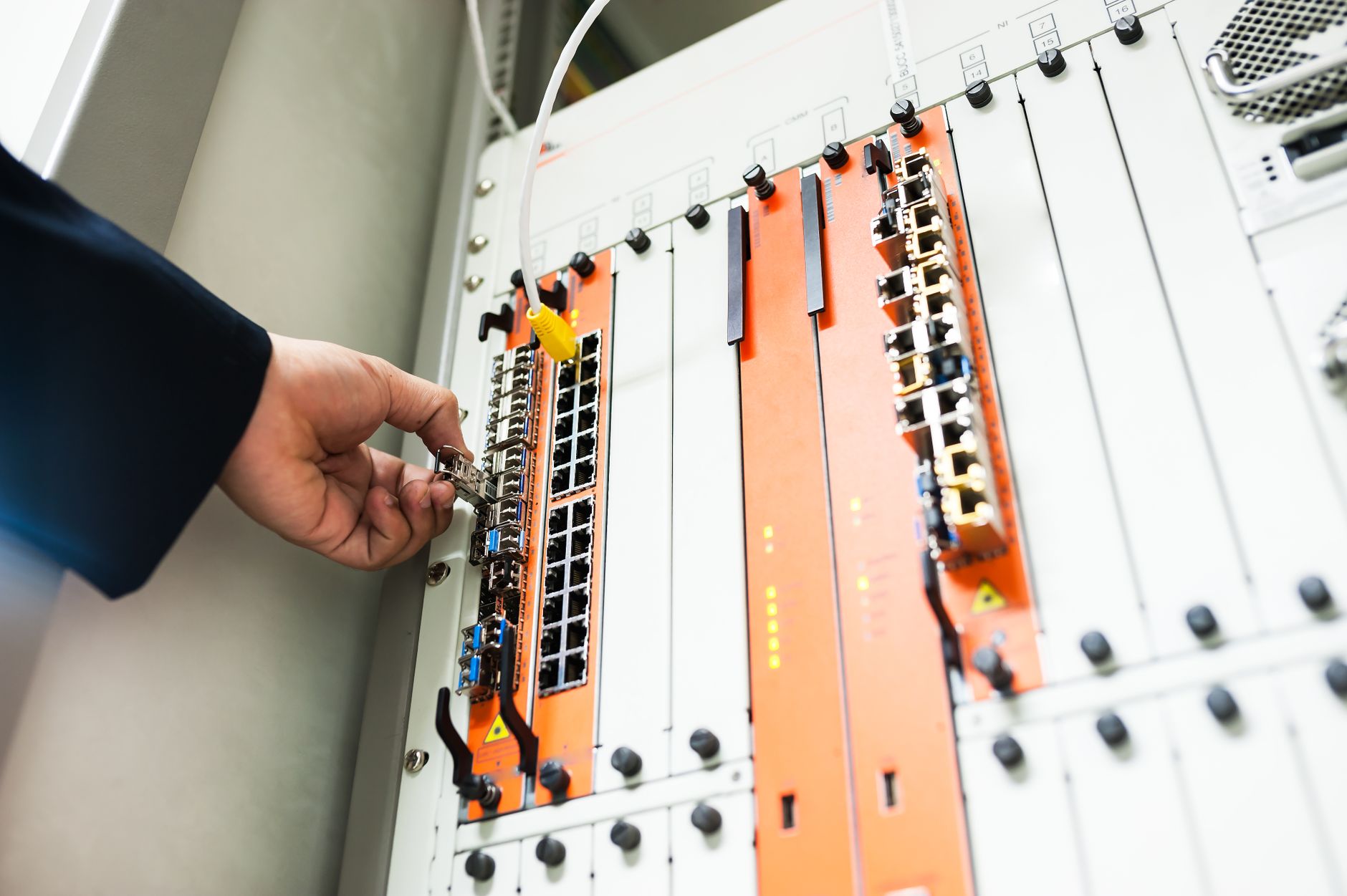 how to troubleshoot a router - Close-up of a hand adjusting network equipment in a data center.