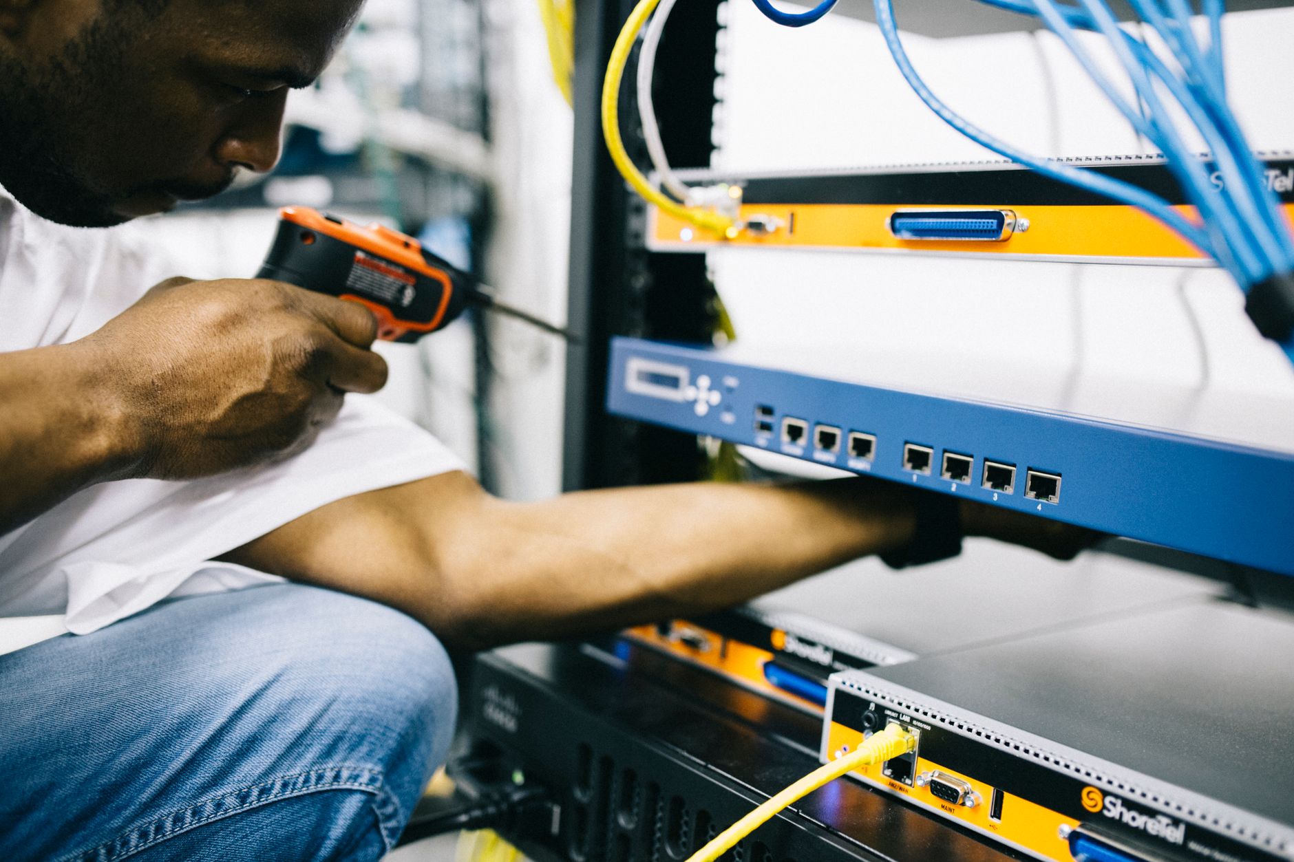 how to troubleshoot internet - Side view crop concentrate African American male mechanic in jeans and white shirt using screw gun while working with hardware