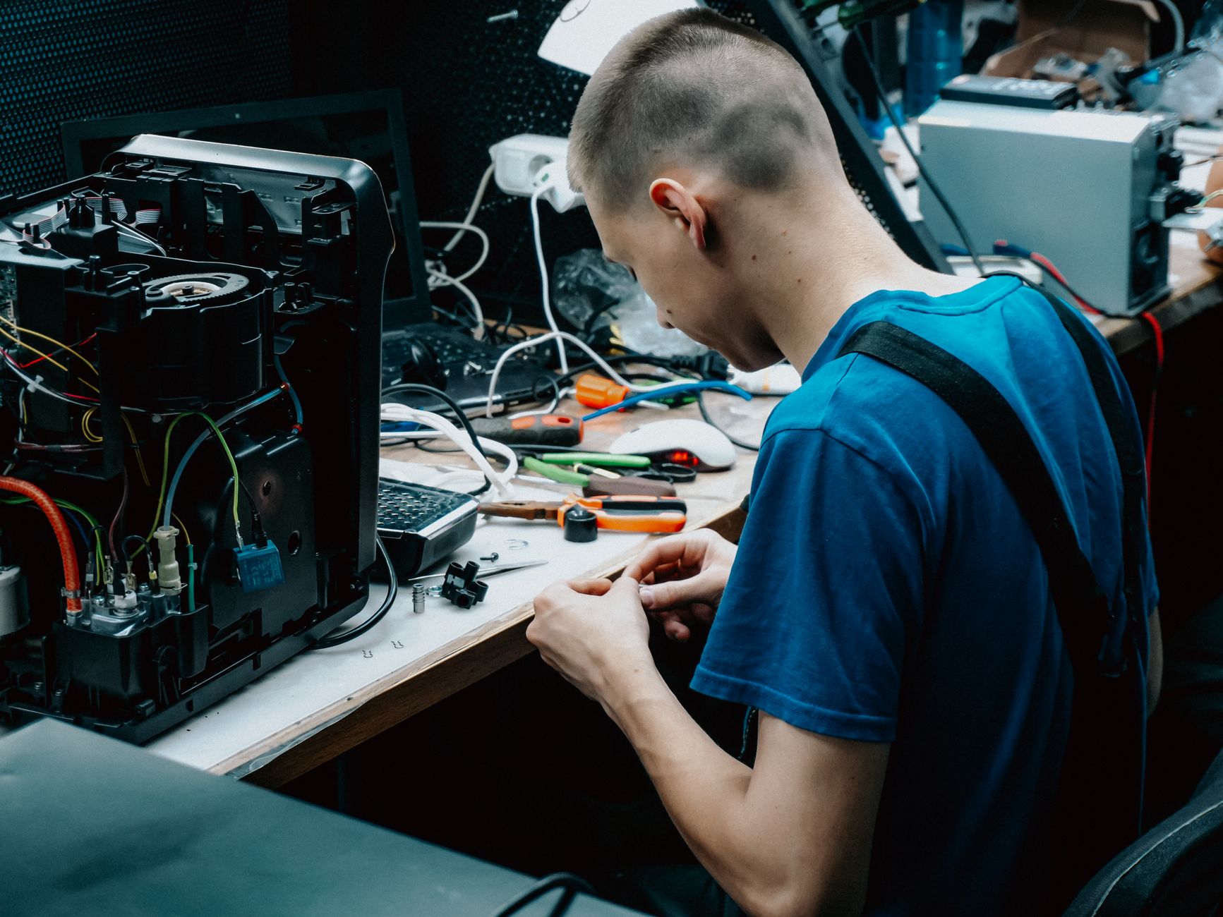how to troubleshoot internet - Skilled technician seated at a workbench repairing electronic devices in a workshop setting.