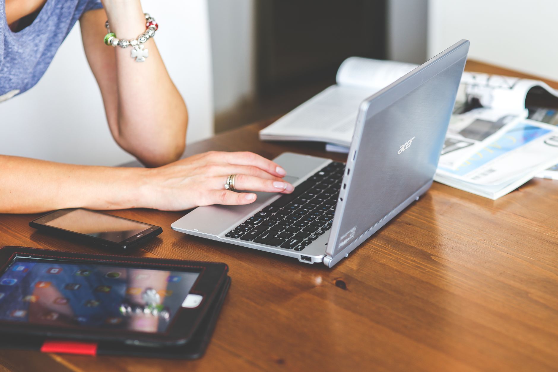 internet but no connection - Woman working remotely on a laptop with mobile devices on a wooden desk.