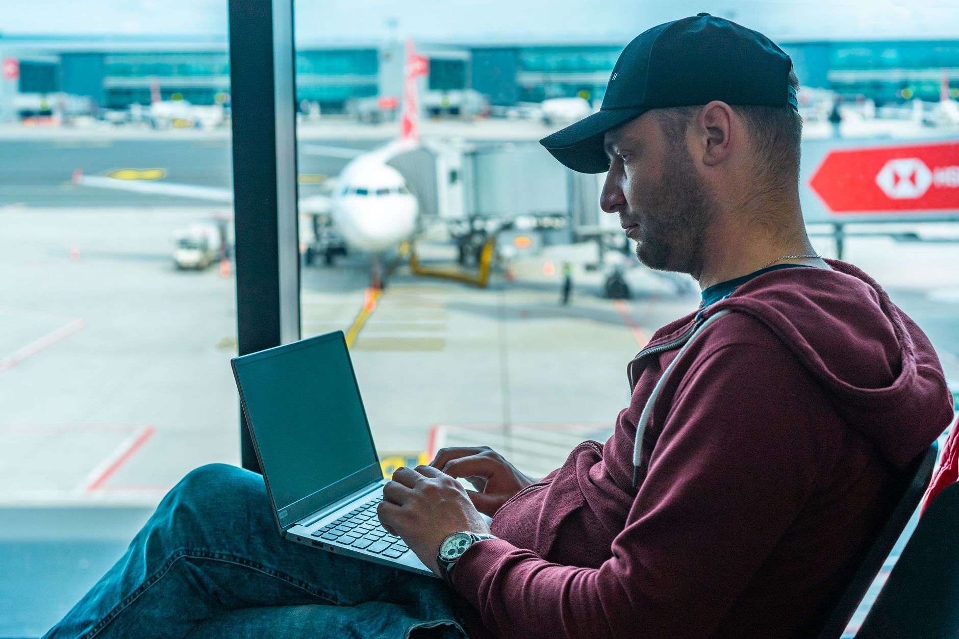 microsoft surface won't connect to wifi - A man working on his laptop in an airport terminal, with a plane visible outside.