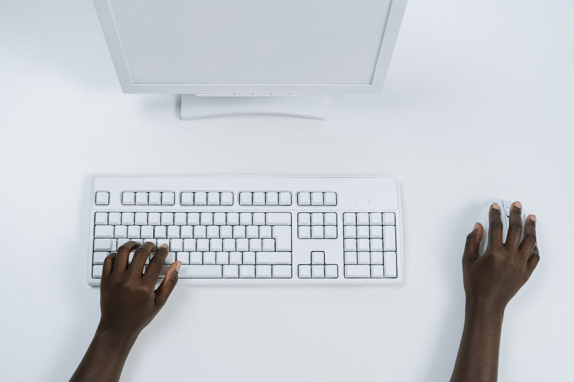 pc says connected but no internet - Top view of a minimalist workspace with a computer and keyboard, featuring dark-skinned hands using mouse and keyboard.