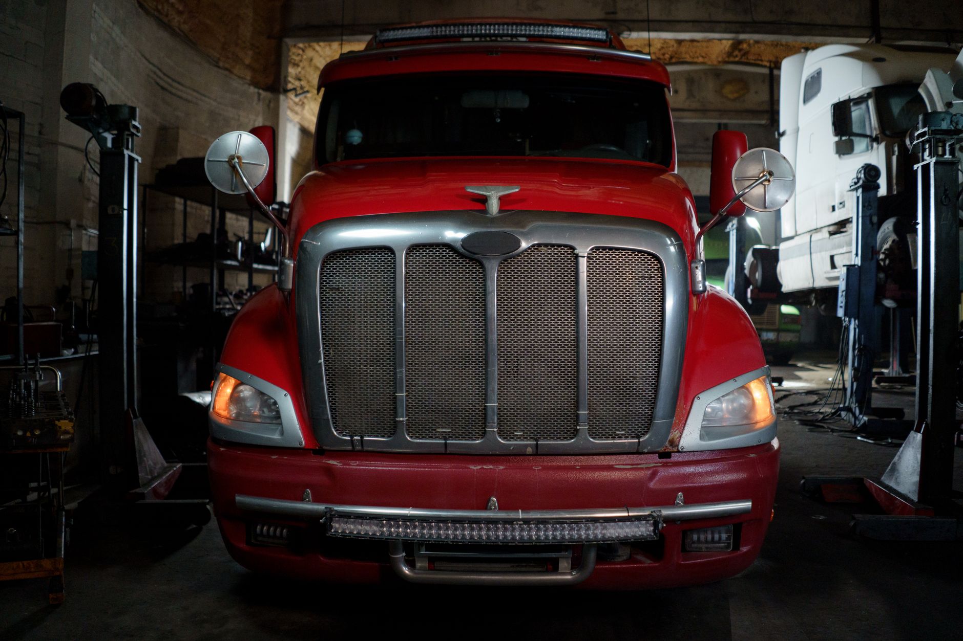 route 19 heavy truck repair - Front view of a red truck parked in a dimly lit industrial garage setting.