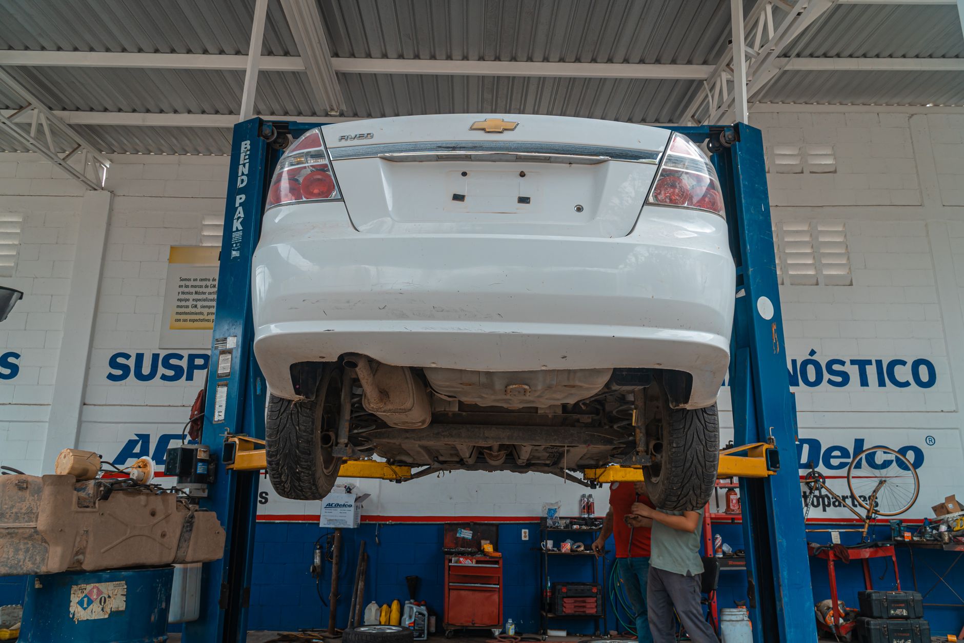 route 401 auto repair - A white Chevrolet car is lifted for maintenance in an automotive repair shop.
