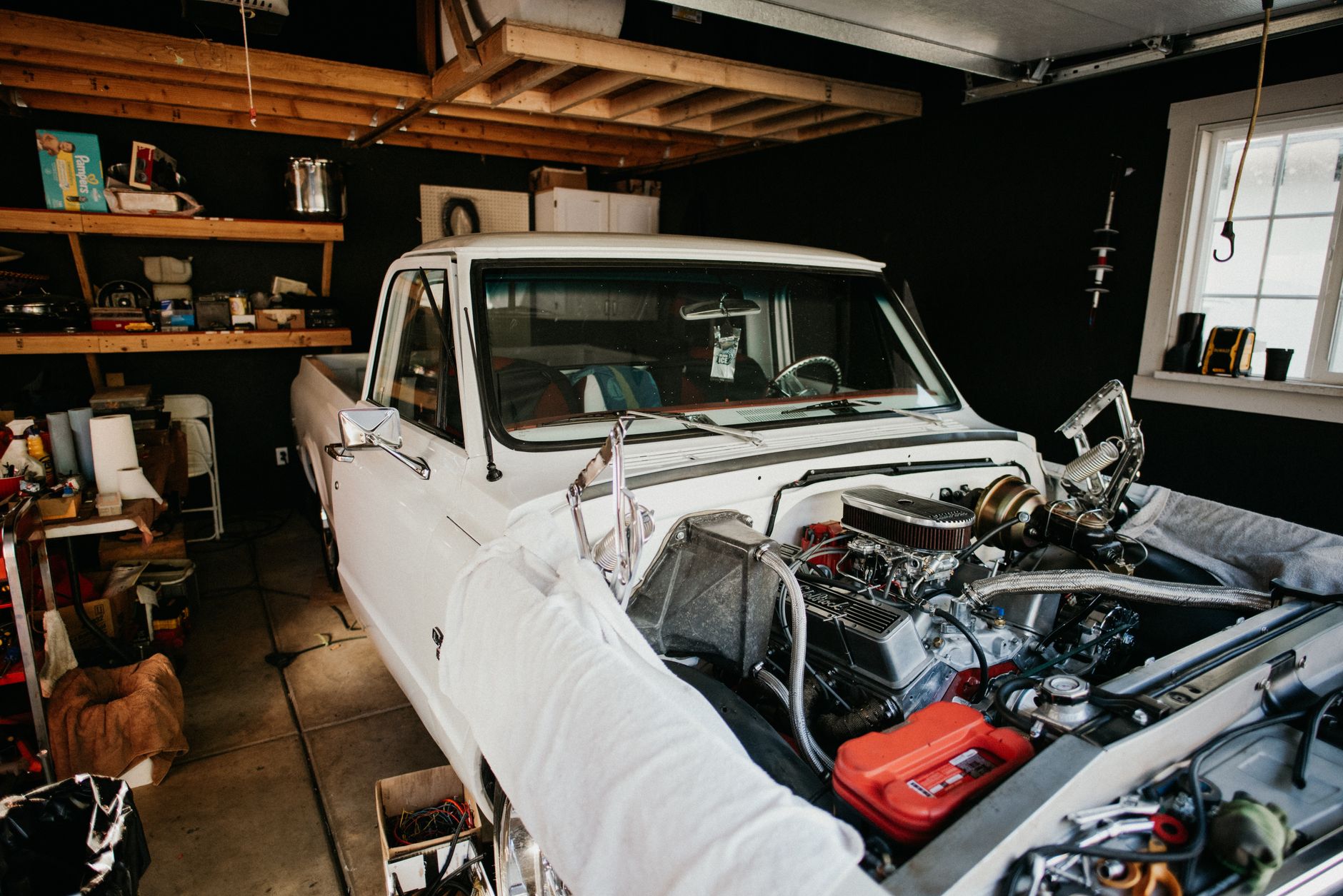 route 401 auto repair - A vintage pickup truck undergoing engine repairs in a well-equipped home garage.