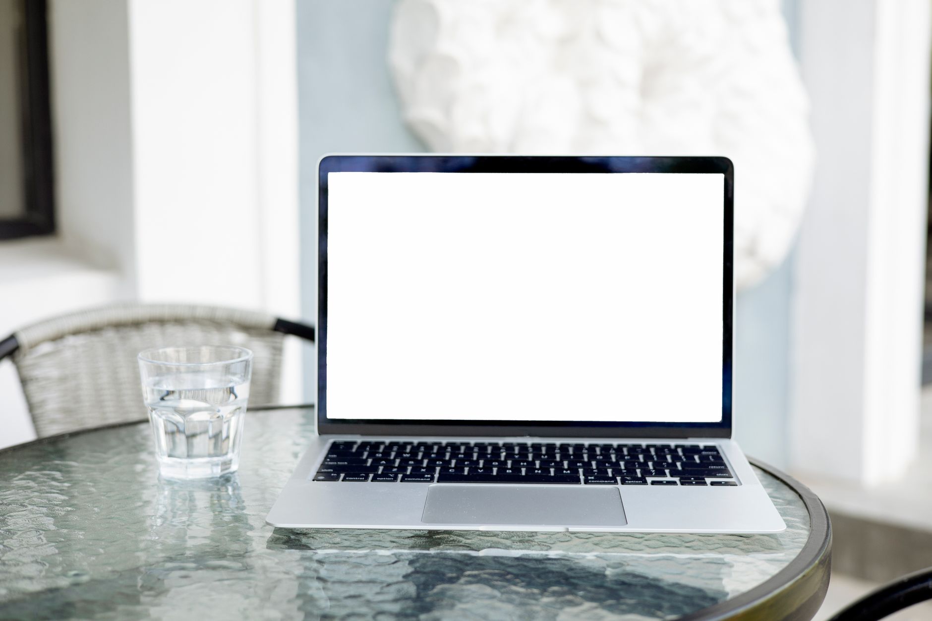 why won't computer connect to wifi - Image of an open laptop with a blank screen on a glass table, next to a glass of water.