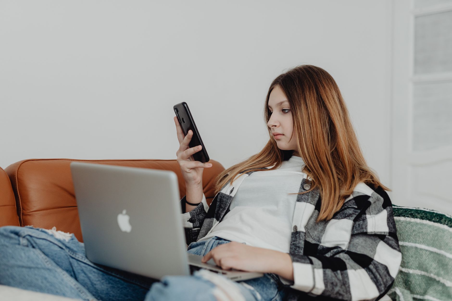 why won't my devices connect to wifi - Teen girl enjoying leisure time on a sofa with smartphone and laptop indoors.