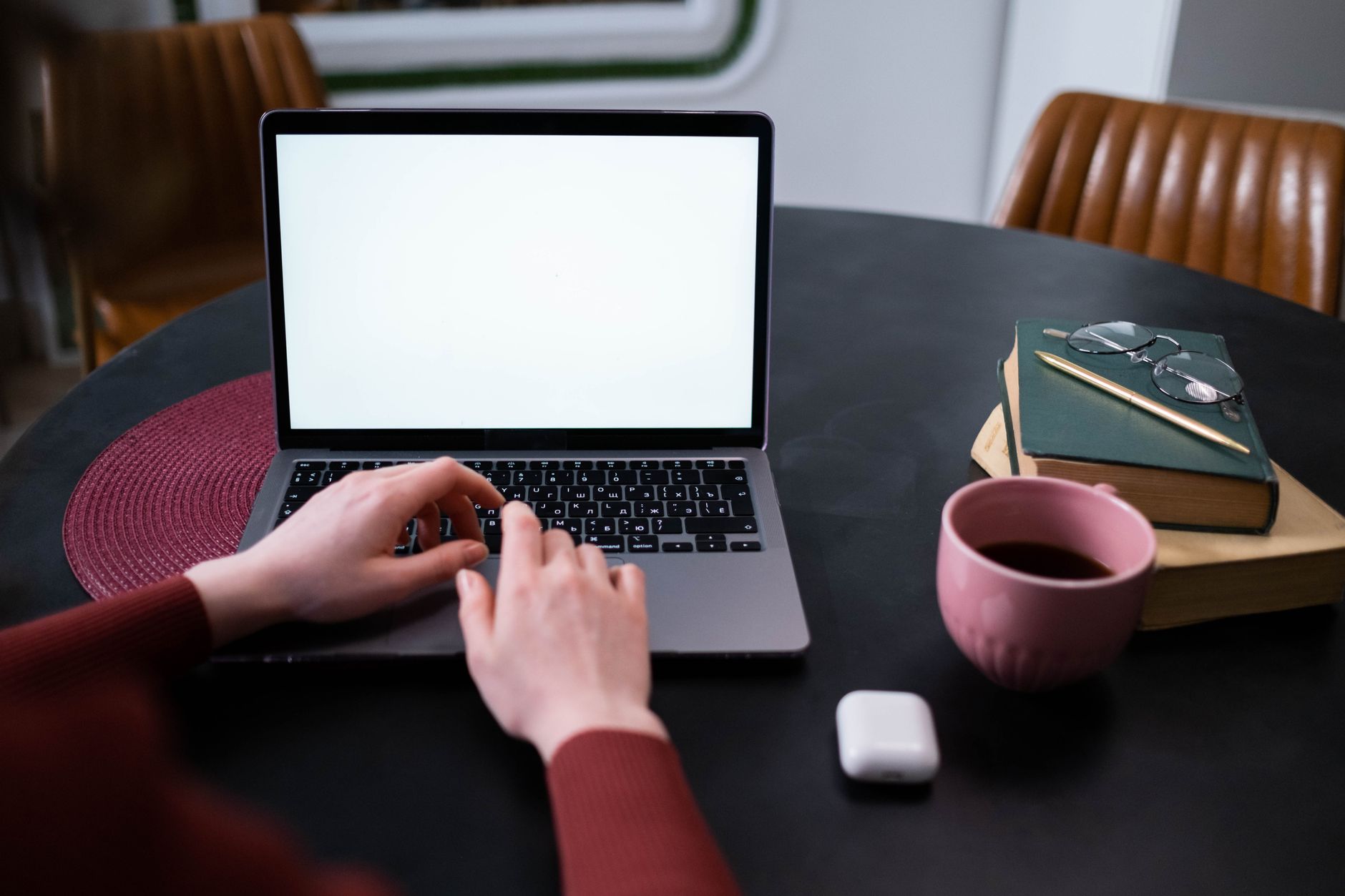wifi adapter not working windows 11 - Hands typing on a laptop at a home office setting with coffee, books, and earphones.