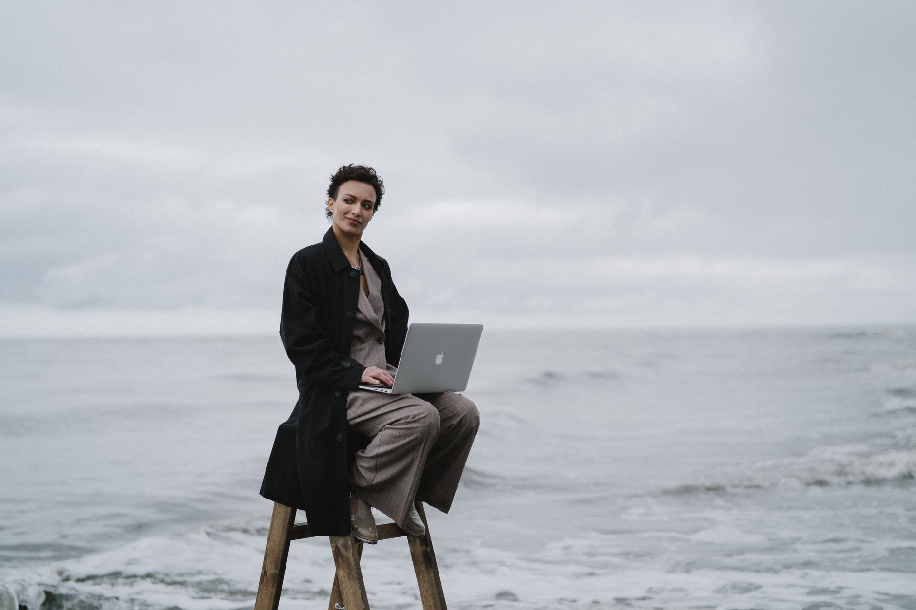 wifi adapter not working windows 11 - A person with a laptop sitting on a ladder by the ocean, symbolizing remote work.
