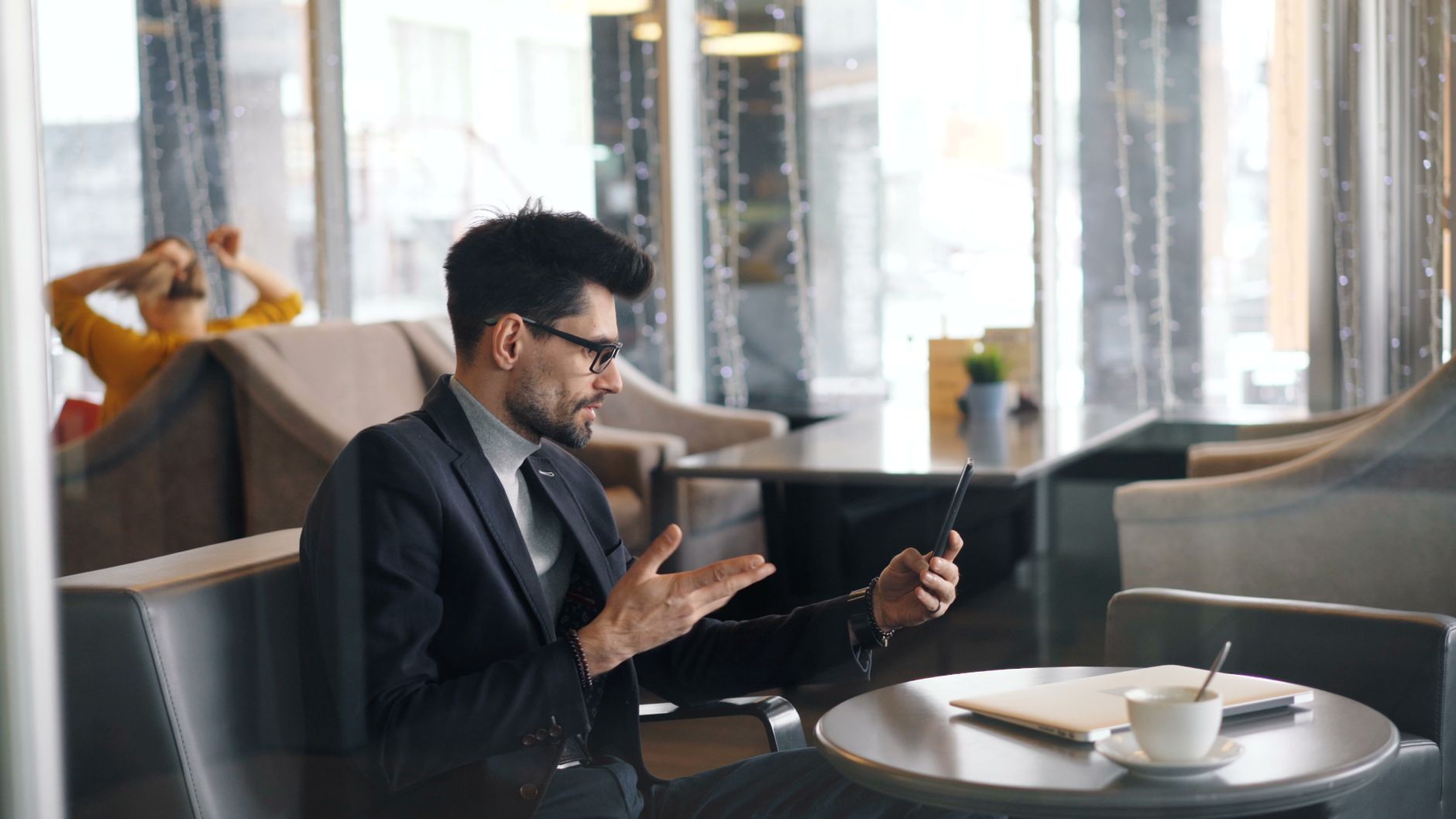 wifi is working on phone but not on laptop - Businessman making a video call in a stylish cafe, using technology for communication.
