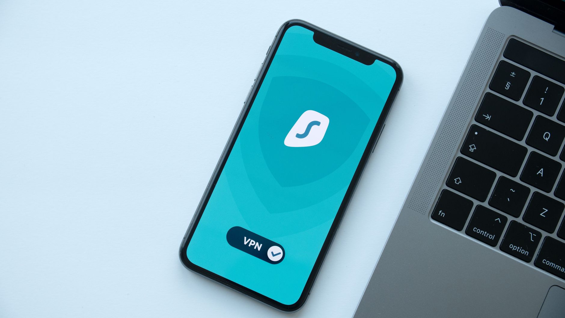 wifi is working on phone but not on laptop - Flat lay of a smartphone showing a VPN app next to a laptop on a desk.