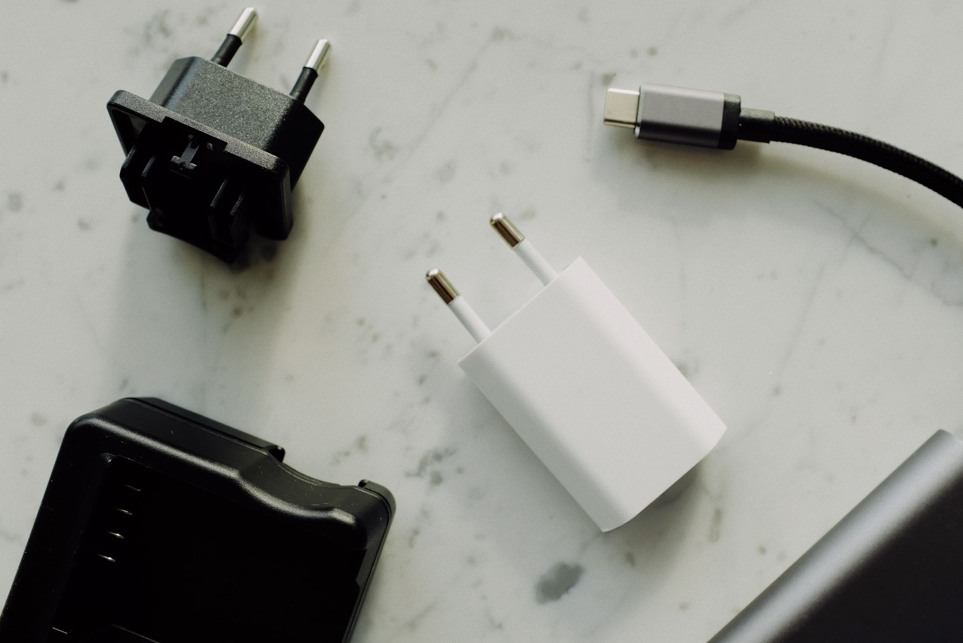 wifi usb adapter not working - Collection of power adapters and a USB-C charging cable on a marble surface.