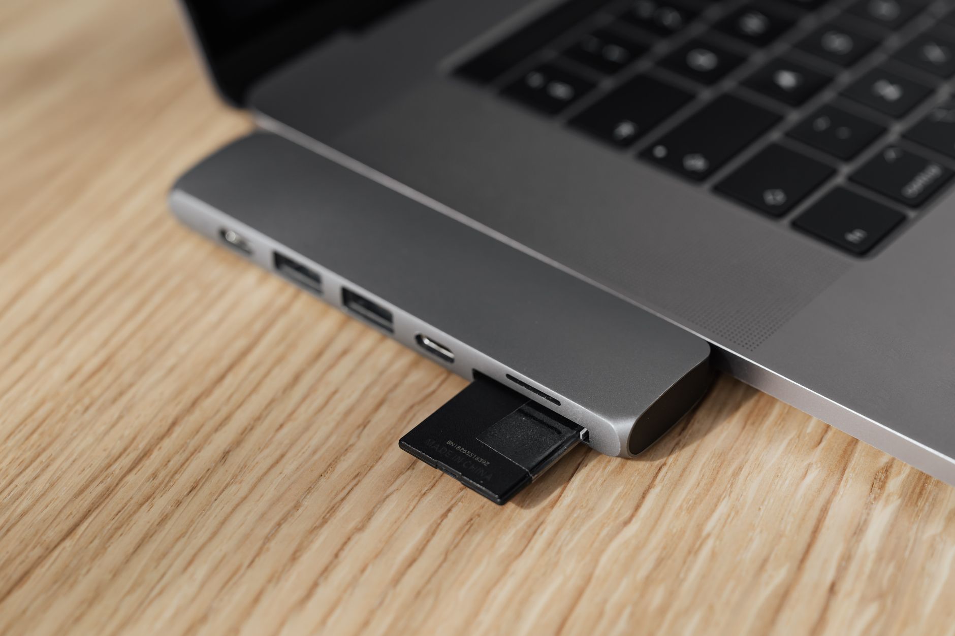 wifi usb adapter not working - Closeup of smart usb port multiplier with inserted memory card connected to modern thin netbook while placed on wooden table