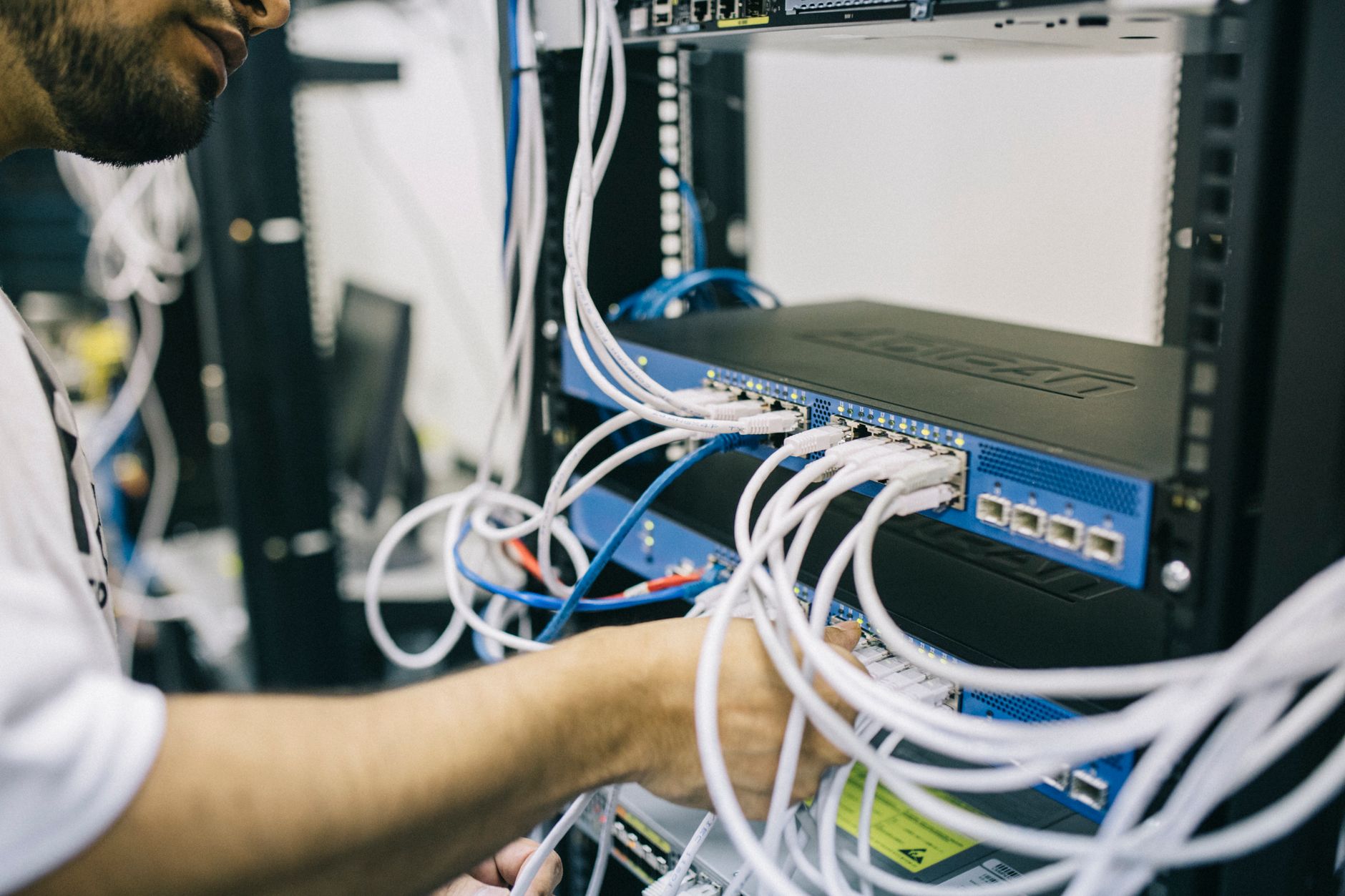 wifire won't connect - An IT professional configuring network cables in a server rack, focusing on Ethernet connections.