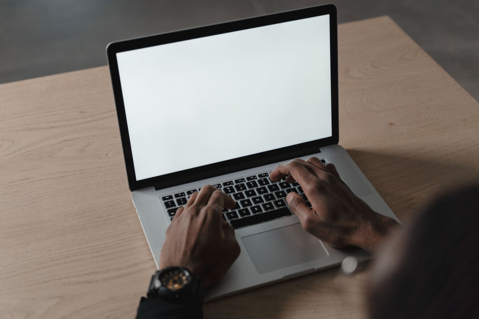 win 10 wifi not working - A person typing on a laptop with a blank screen on a wooden desk, ideal for mockups.