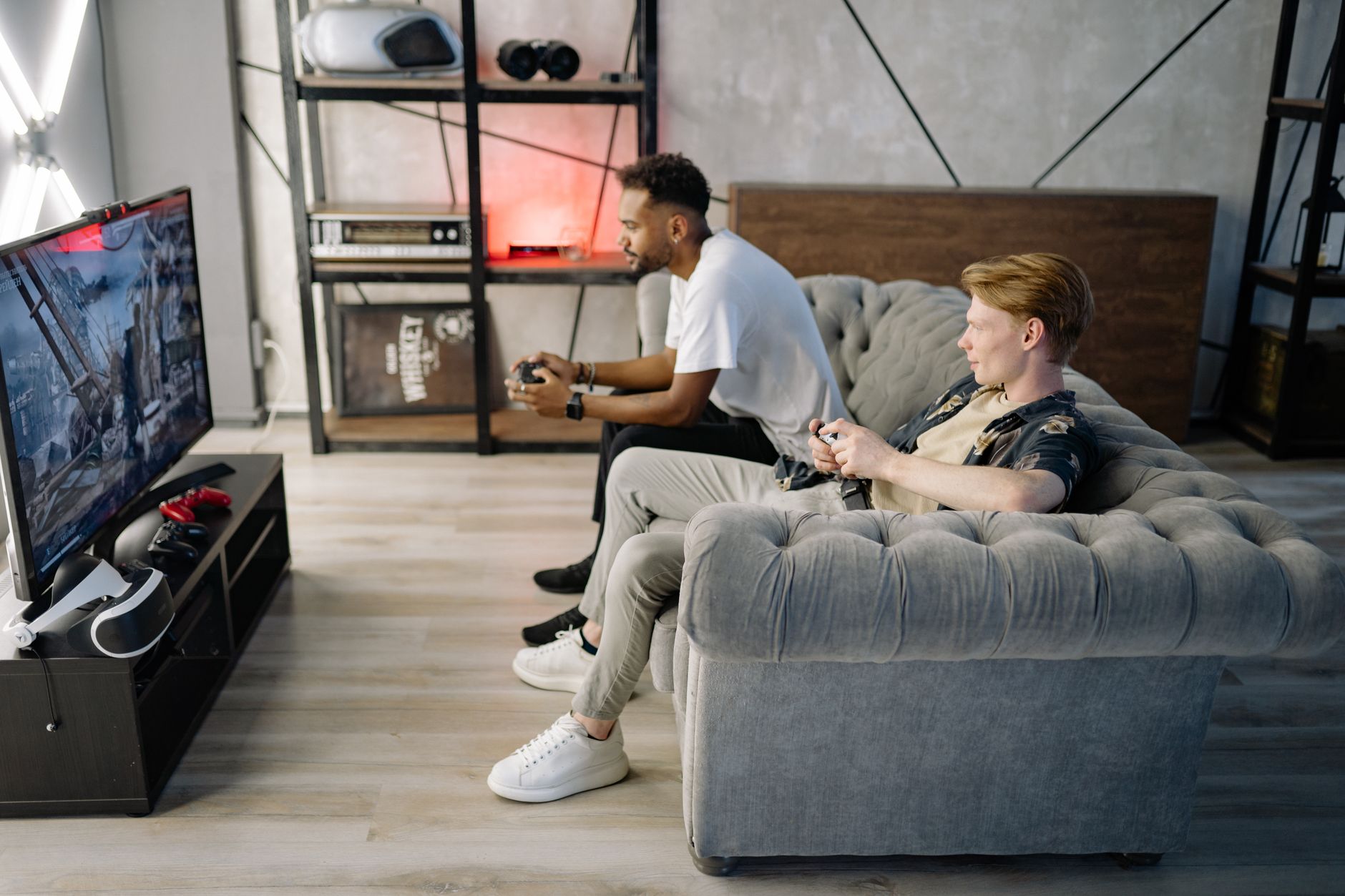 xbox won t connect to wifi but everything else does - Two adult men playing video games on a couch, enjoying leisure time indoors.